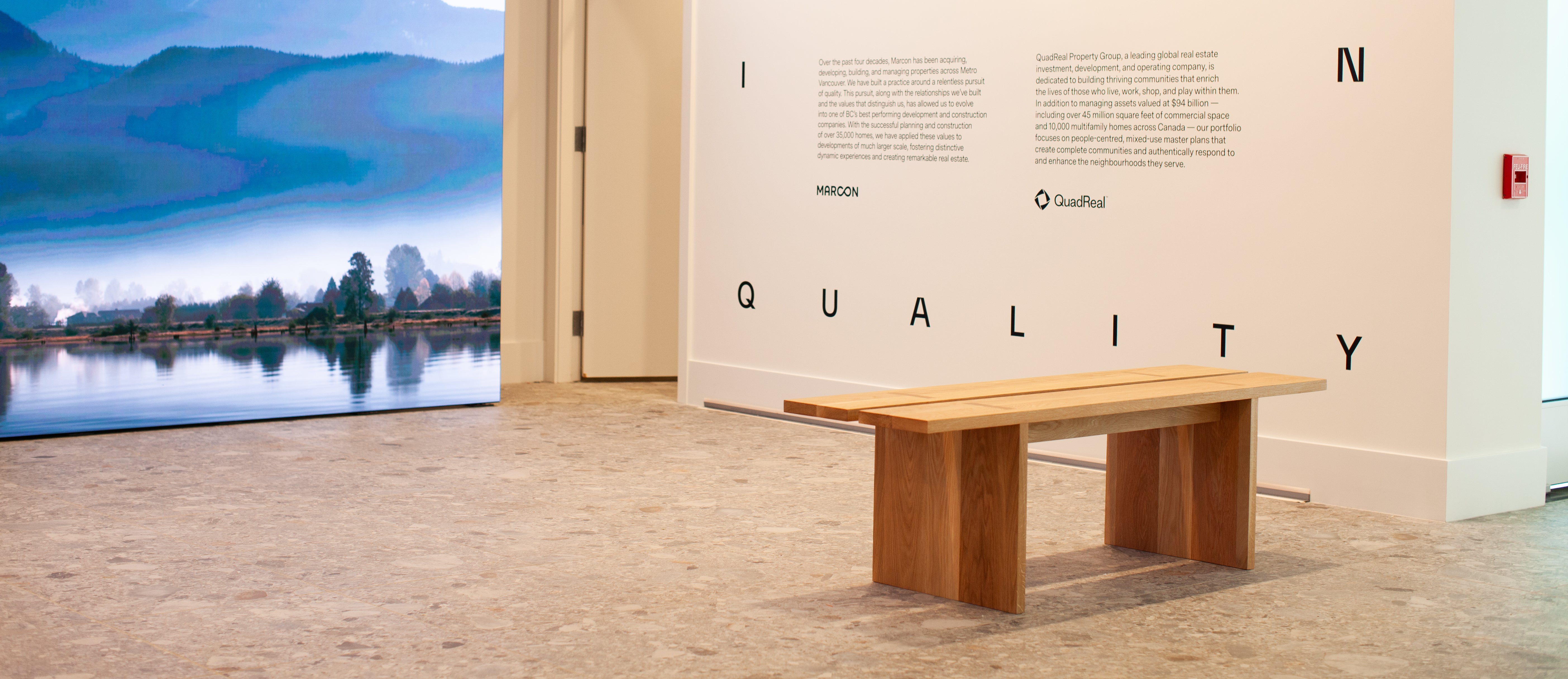 Wooden bench in a room with a large screen displaying a scenic view.
