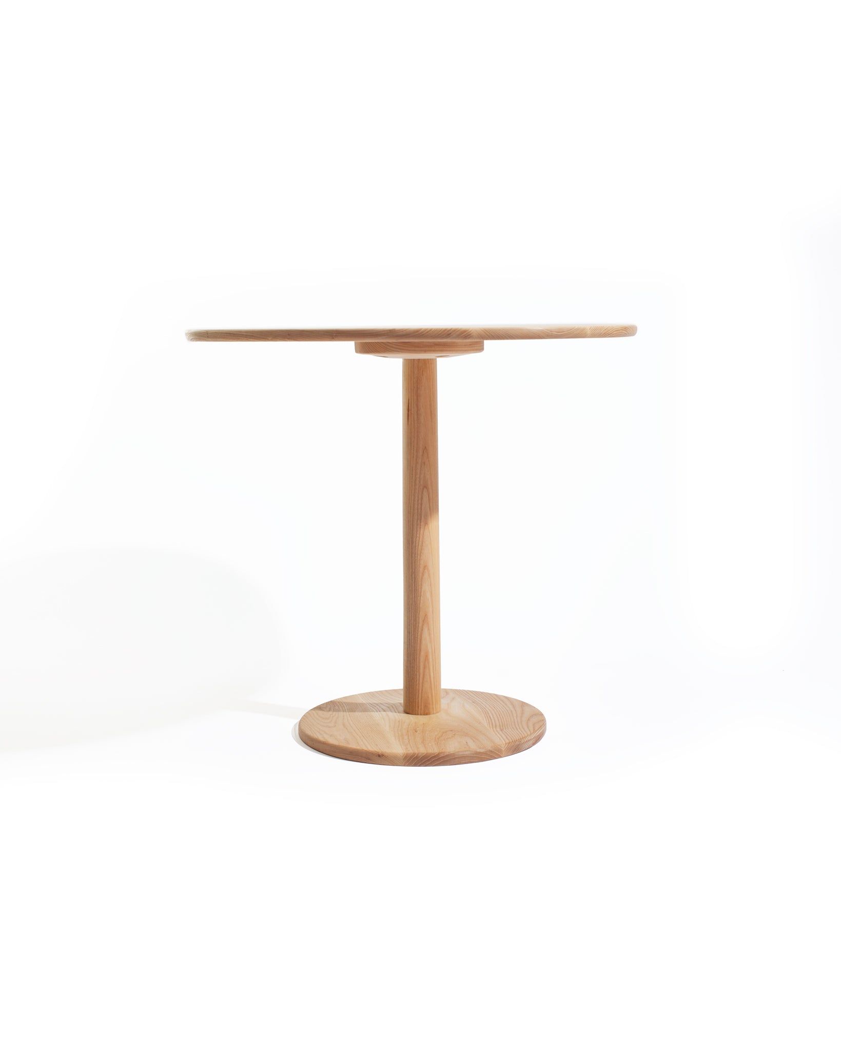 Ash wood tulip-style dining table on white backdrop