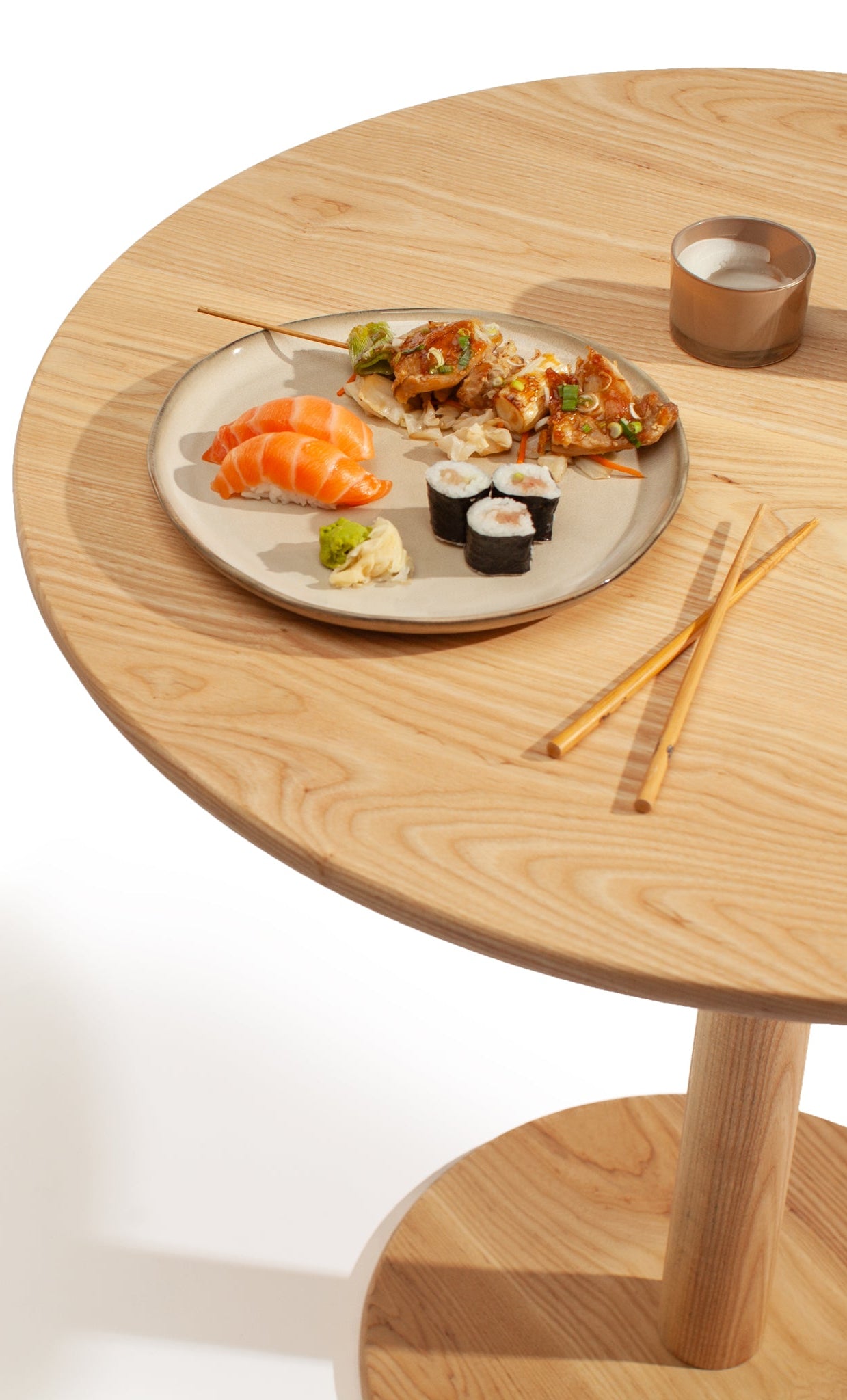Solid ash tulip table with sushi arrangement on white background