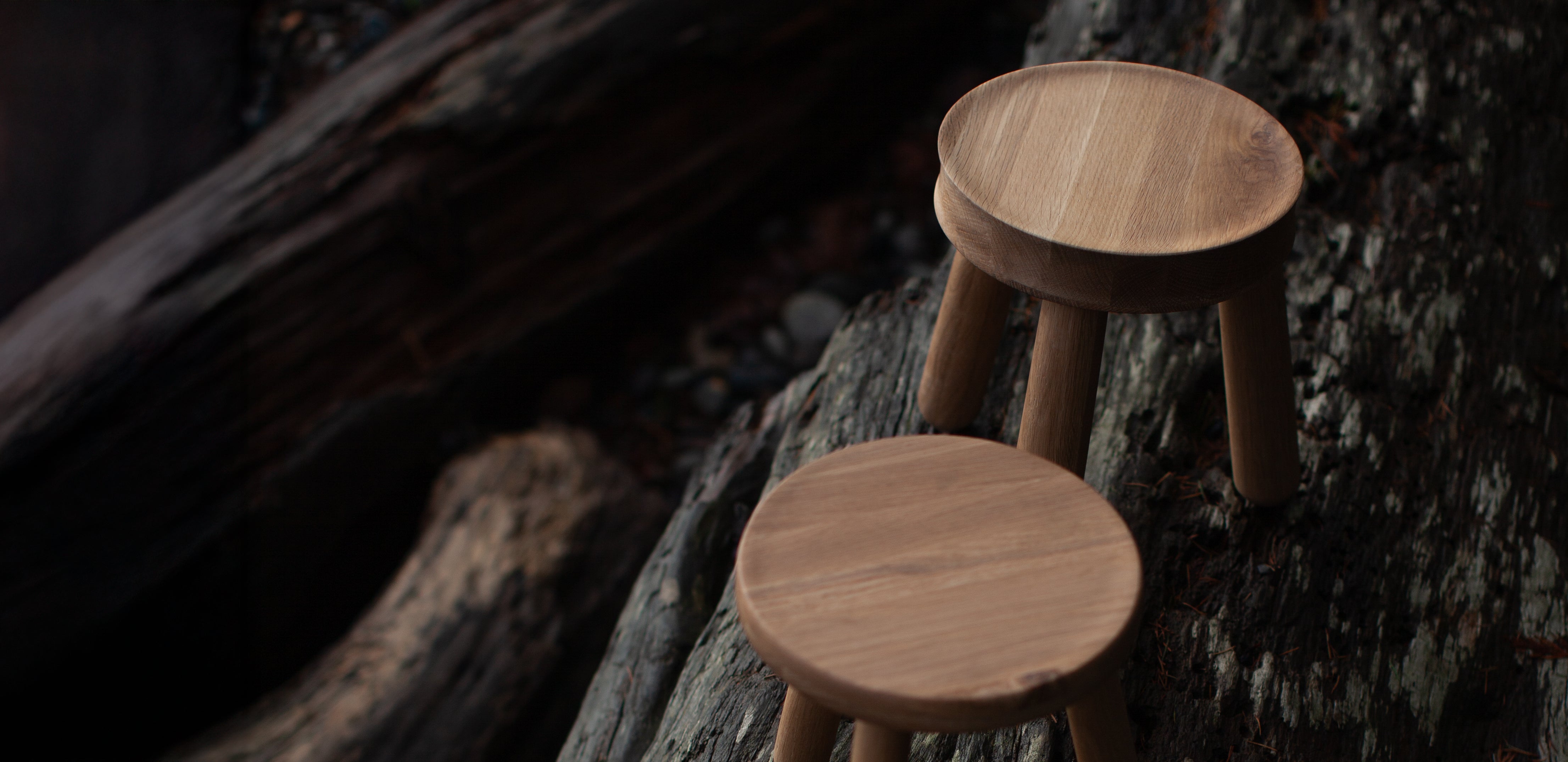 Two wooden stools on a tree stump with a dark background